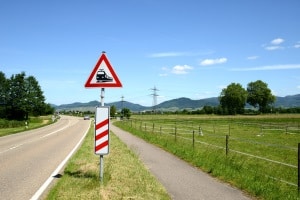 Das Verkehrsszeichen Nr. 151 zusammen mit einer Entfernungsbake: Sie kündigen den Bahnübergang an.